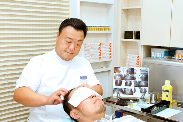 男性患者の頭皮を診察する吉澤院長